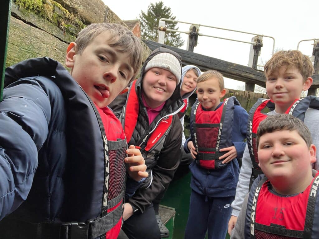 A group of young people at the tiller deck of a narrowboat. 